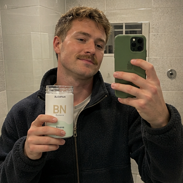 A 3x3 collage showing a woman and a man holding and taking mirror selfies with a jar of Bionica 'Sapna' body butter. The scenes include a bathroom, a bedroom, a park, and inside a car, with some panels showing the product jar prominently and others showing it in context on a counter or in a travel bag.